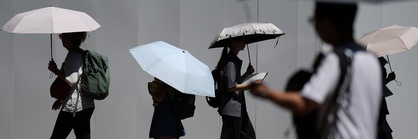 Personen laufen über eine Straße und halten Regenschirme in der Hand.