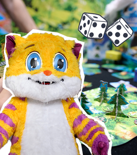 Ein Brettspiel und davor das Maskottchen der Spielemesse - eine große gelb-lila-gestreifte Katze.