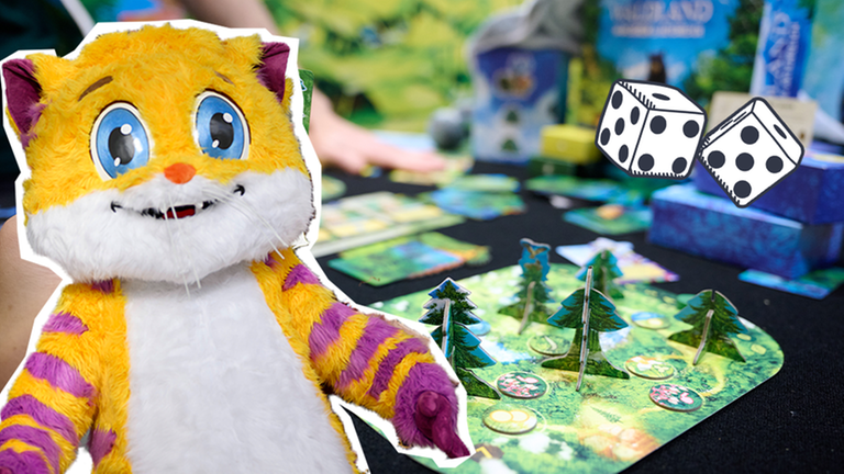 Ein Brettspiel und davor das Maskottchen der Spielemesse - eine große gelb-lila-gestreifte Katze.