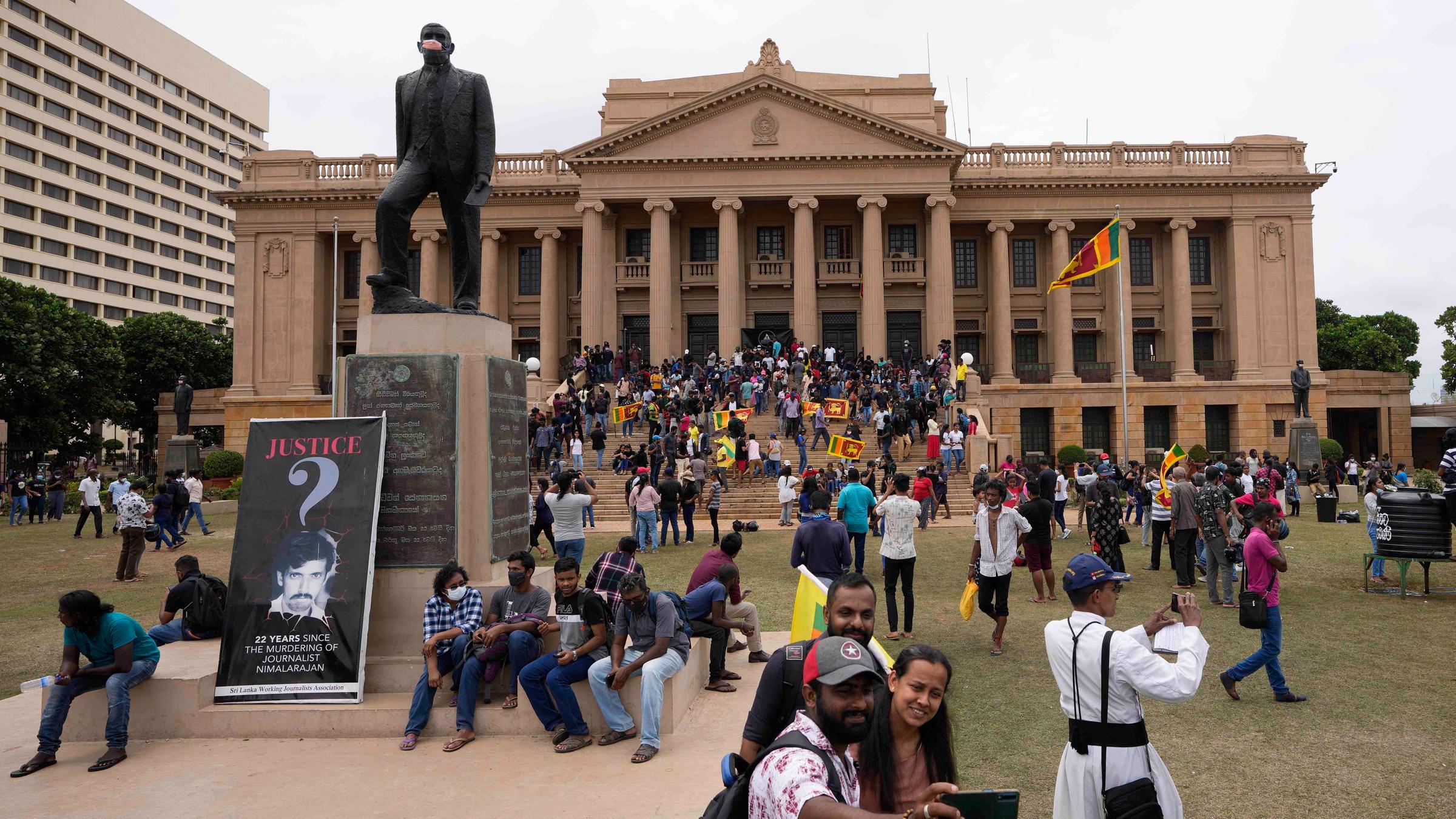 Demonstranten haben den Präsidentenpalast in Sri Lanka gestürmt und bewegen sich nun auf dem Rasen vor dem Gebäude.