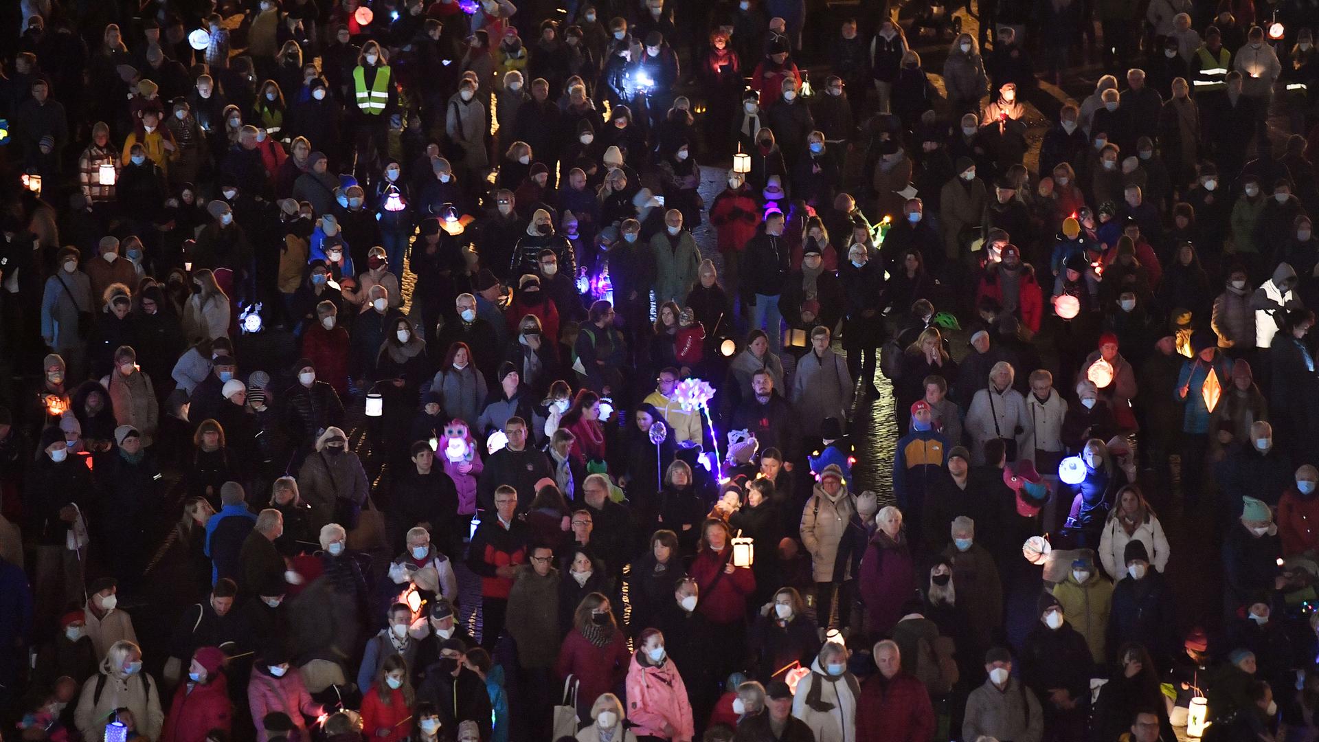 Kinder gehen in der Dämmerung mit Laternen spazieren, vorneweg reitet jemand als St. Martin verkleidet.