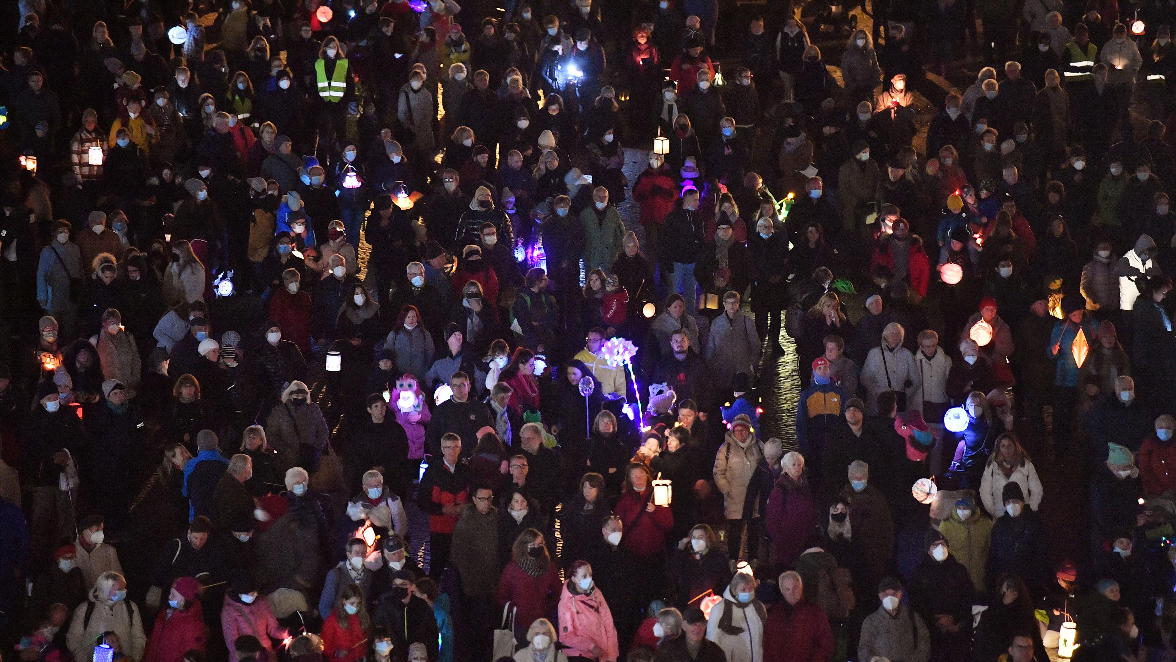Kinder gehen in der Dämmerung mit Laternen spazieren, vorneweg reitet jemand als St. Martin verkleidet.