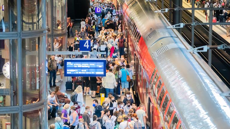 Überfüllter Bahnsteig von oben, eine Regionalbahn ist eingefahren. 