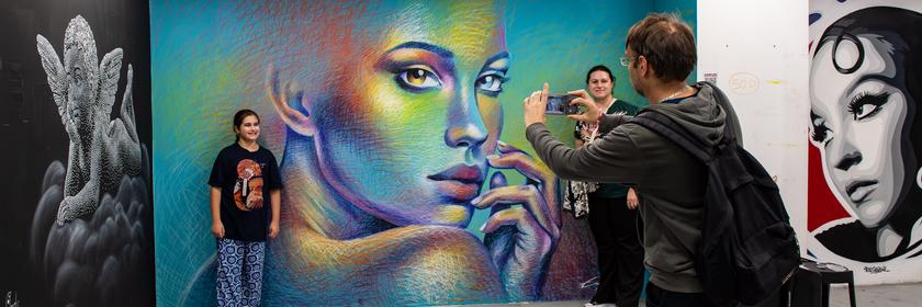 Ein Mädchen lässt sich vor einem großen Gemälde in der StreetArt Austellung "StreetArt Denfert" in Paris fotografieren.
