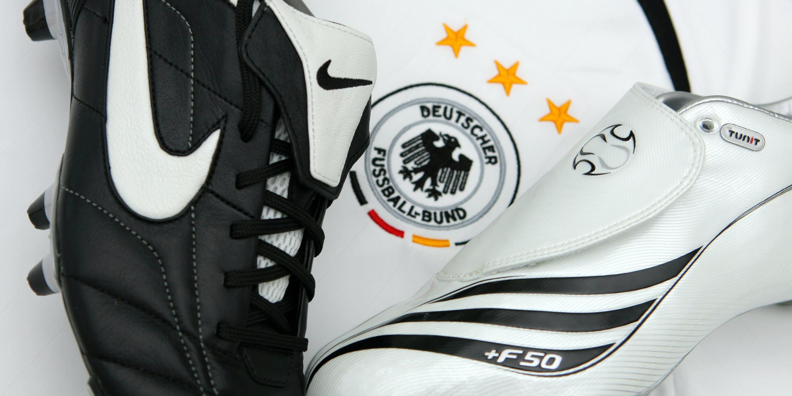 Fußballschuhe von Adidas (r) und Nike liegen auf einem Trikot der deutschen Fußball-Nationalmannschaft.