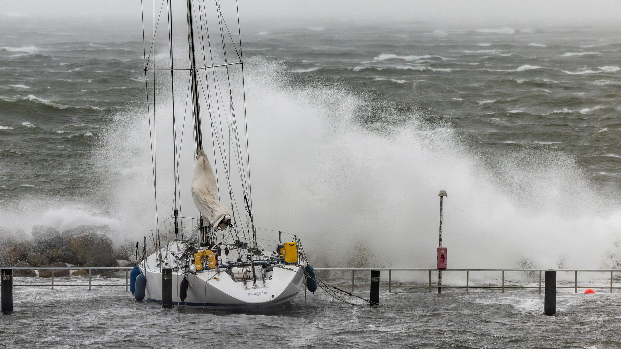Meterhohe Wellen brechen sich an den Hafenanlagen in Schilksee. 