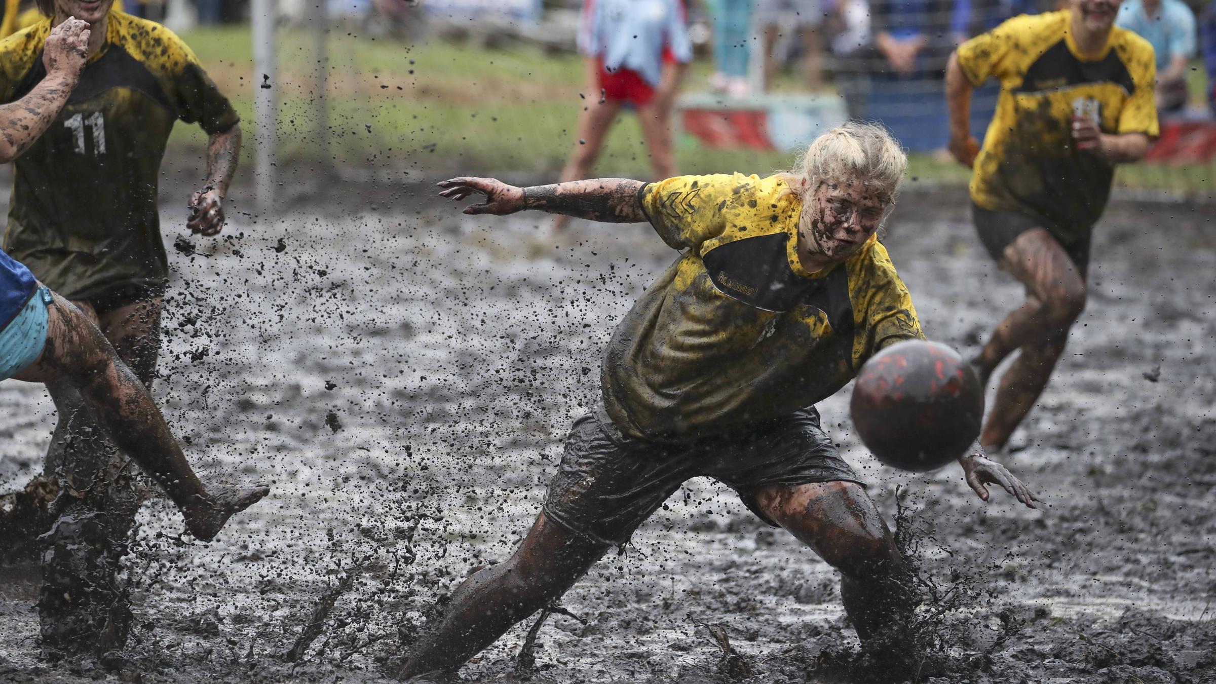 Eine Mädchenmannschaft spielt Fußball im matschigen Sumpf. 