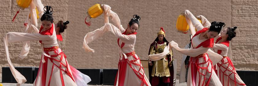 Tänzerinnen vor der chinesischen Mauer in traditionellen Kostümen.