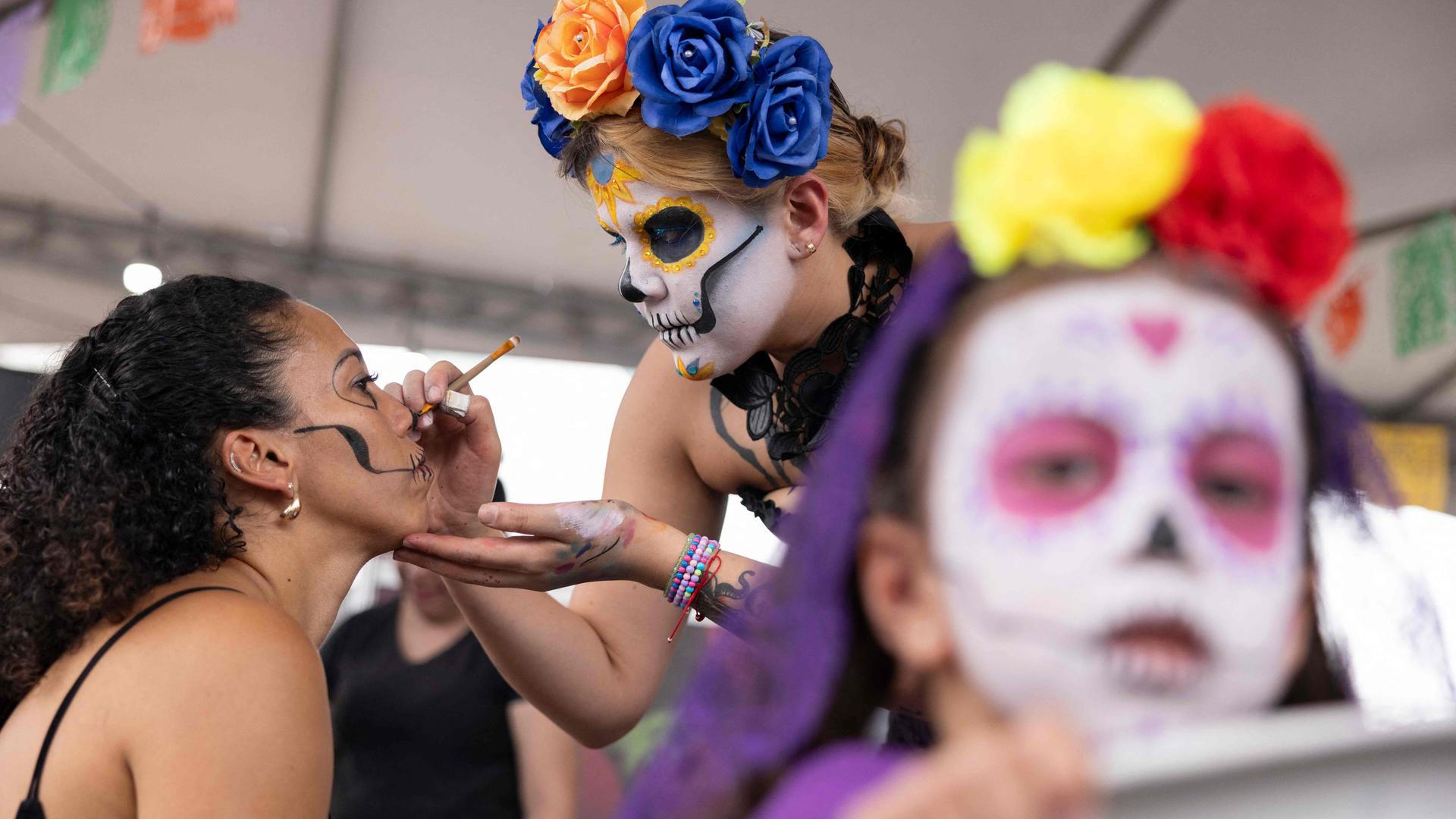 Frauen schminken ihre Gesichter bunt. 