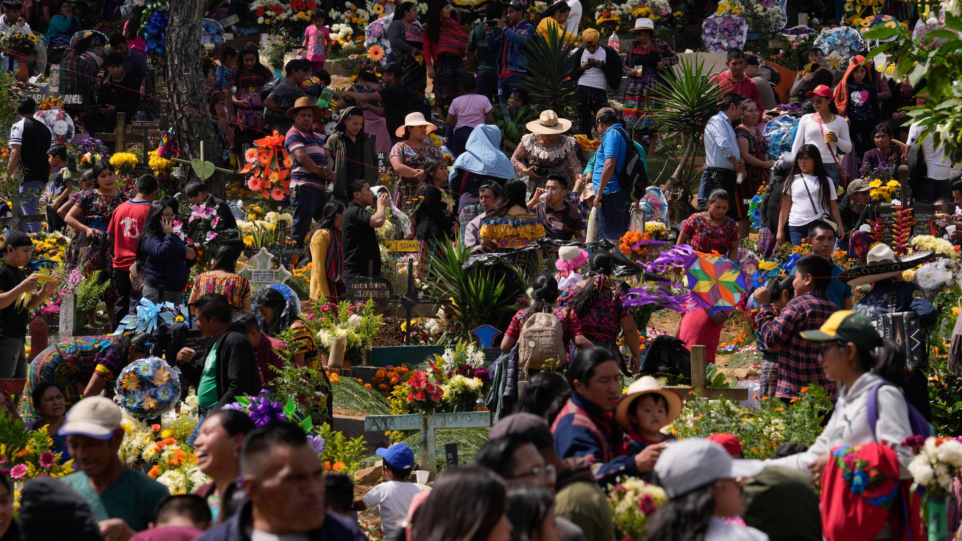 Viele Menschen auf einem bunt geschmückten Friedhof