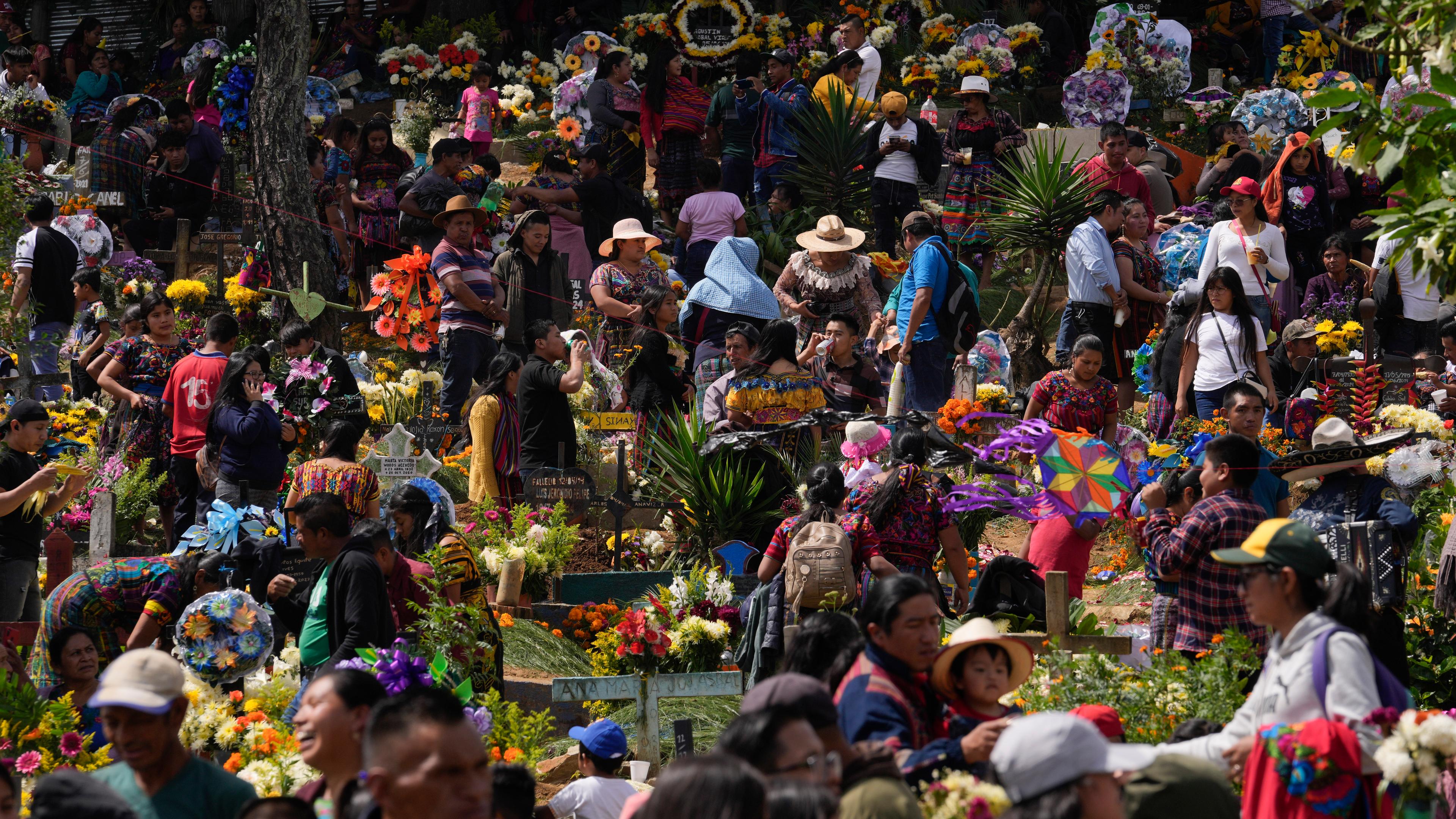 Viele Menschen auf einem bunt geschmückten Friedhof