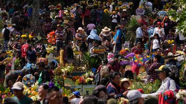 Viele Menschen auf einem bunt geschmückten Friedhof
