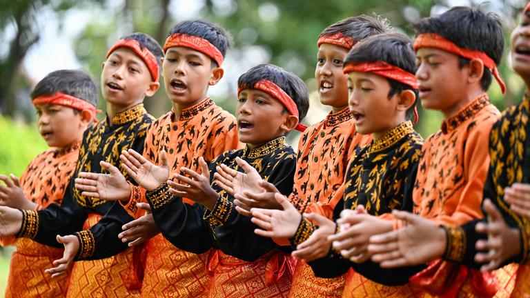 Jungen in traditioneller Kleidung klatschen.