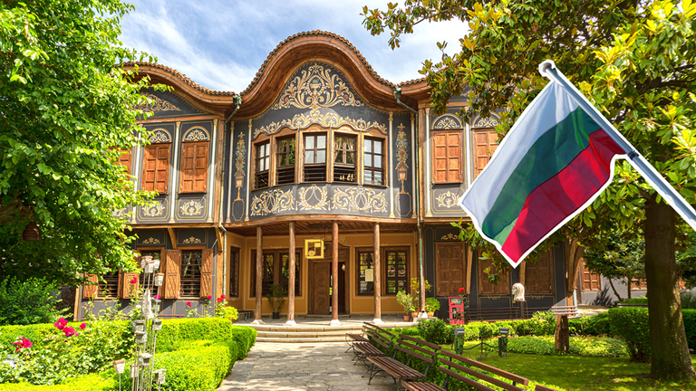 Bulgariens Flagge vor einem traditionellen bulgarischen Haus.