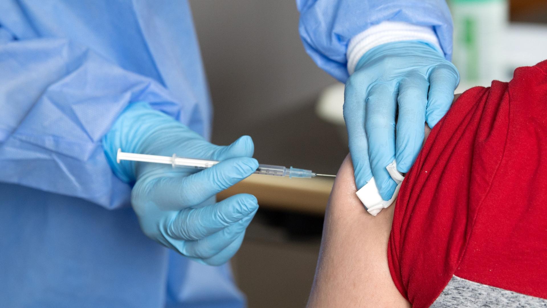 Eine Ärztin impft einen Mann.