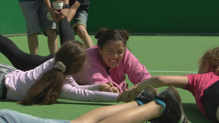 Reporterin Teresa liegt am Boden und wird an den Füßen gezogen