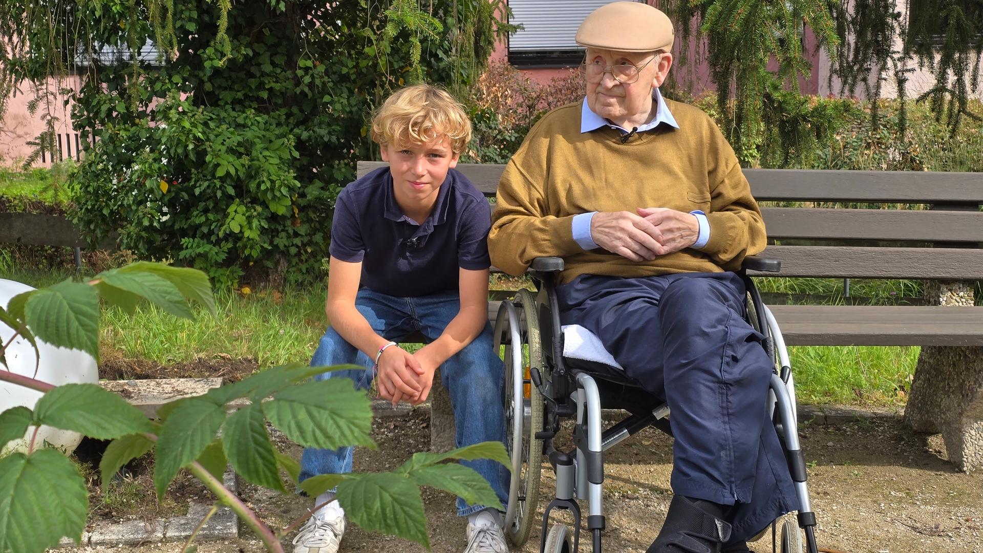 Ein Junge und sein Opa sitzen auf einer Bank im Grünen.