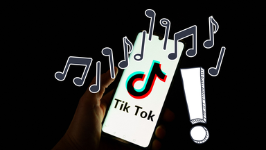 Logo von TikTok auf einem Handy mit Musiknoten und Ausrufezeichen
