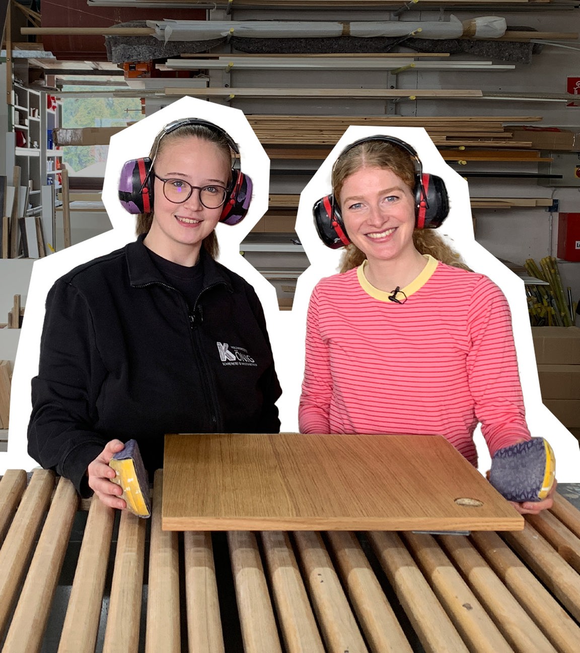 Lara und Lisa stehen vor einem Brett und haben Gehörschutz auf