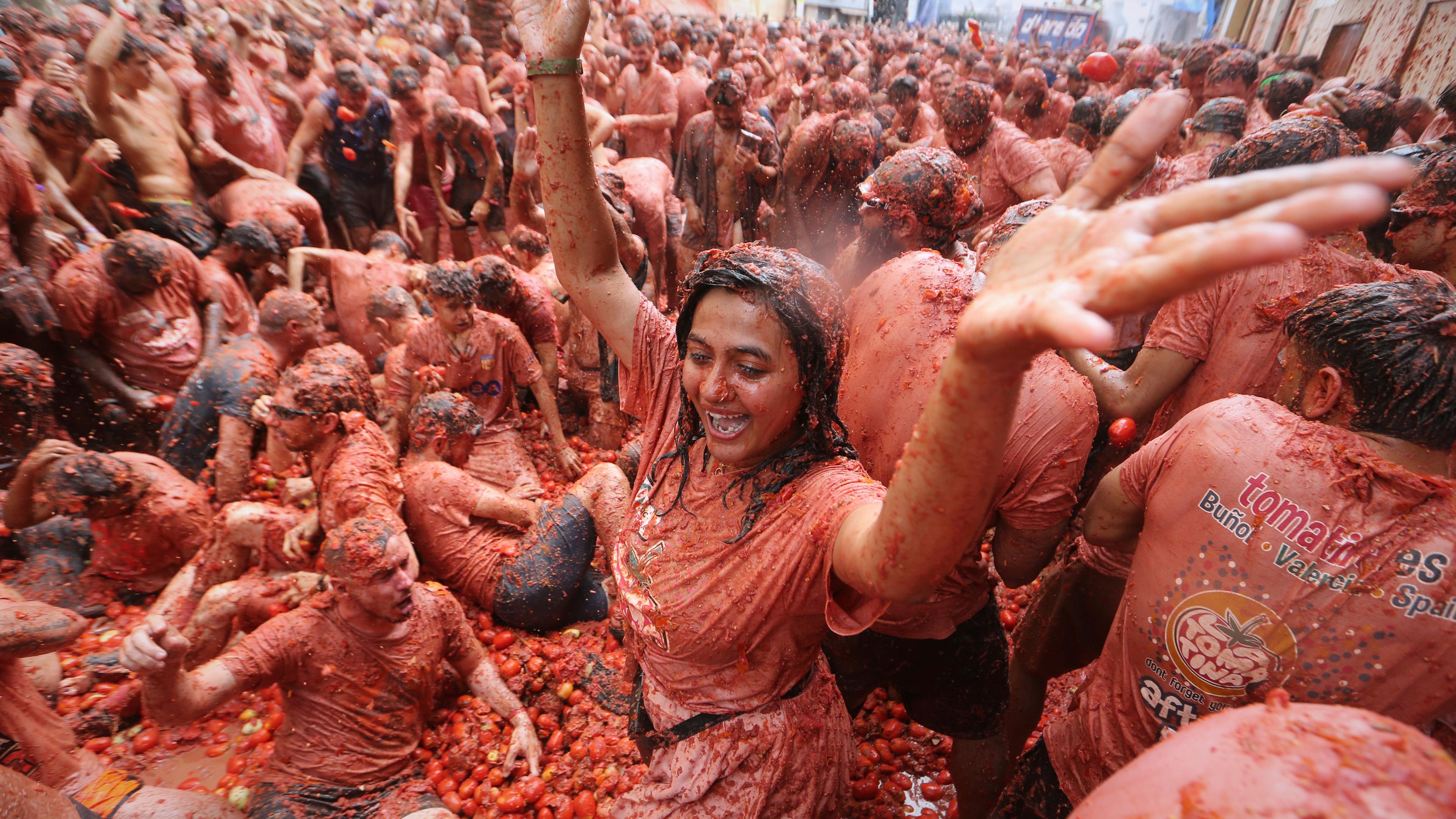 Viele lachende Menschen bewerfen sich mit Tomaten.