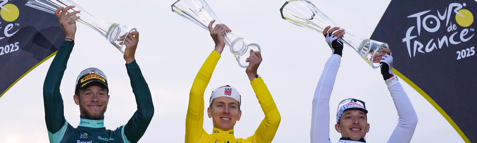Die drei Gewinner der Tour de France halten Pokale in die Luft.