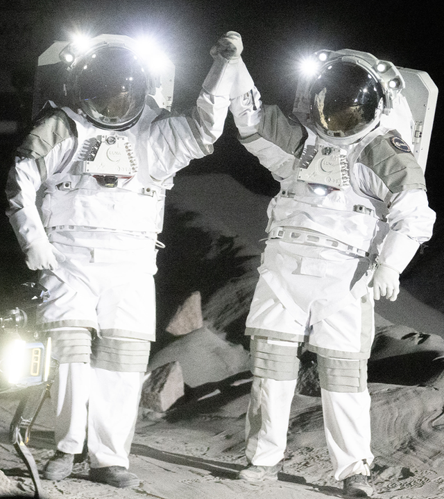 Zwei Astronauten geben sich High-Five, daneben steht ein Schild mit dem Wort Köln