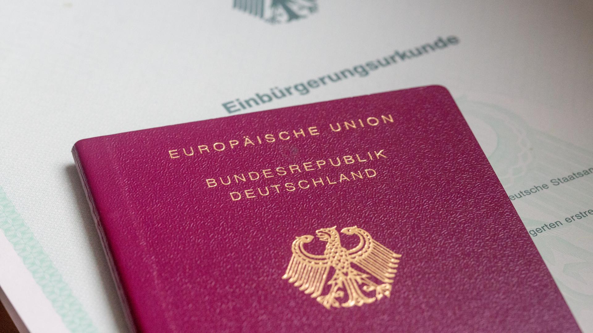 Eine Einbürgerungsurkunde der Bundesrepublik Deutschland und ein deutscher Reisepass liegen auf einem Tisch.