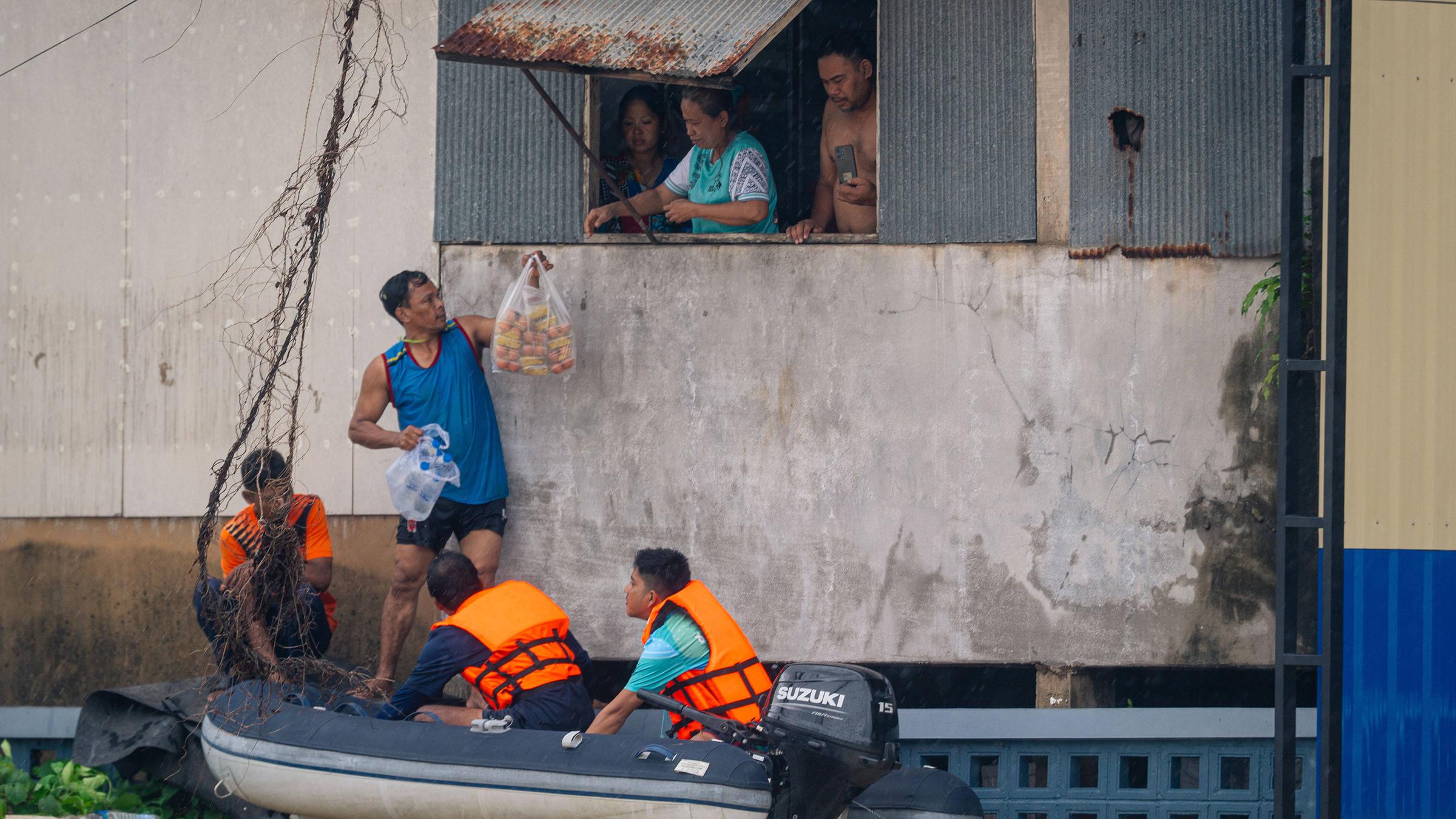 Anwohner sind durch das Wasser in ihren Häusern gefangen. Deshalb bekommen sie Essen von Helfern.