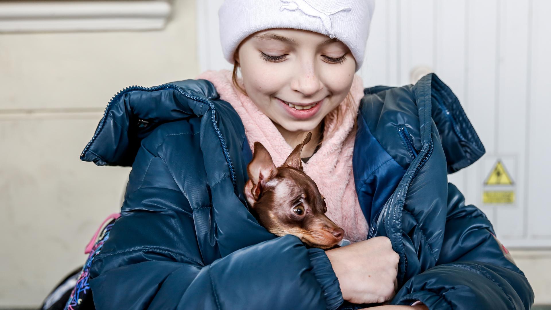 Ein geflüchtetes Mädchen aus der Ukraine hält ihren Hund im Arm.