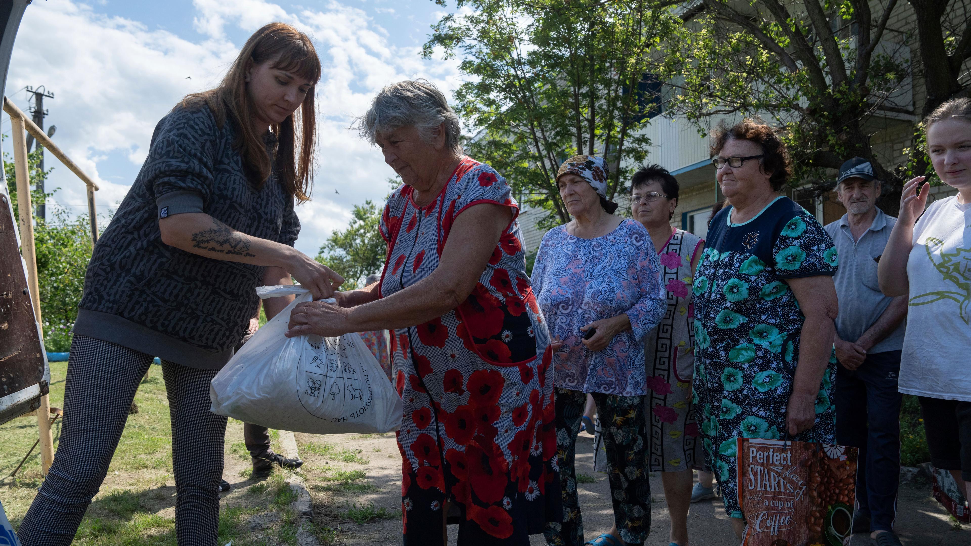 Eine Helferin verteilt Tüten an Bewohnerinen in der Ukraine.