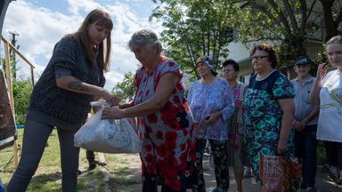 Eine Helferin verteilt Tüten an Bewohnerinen in der Ukraine.