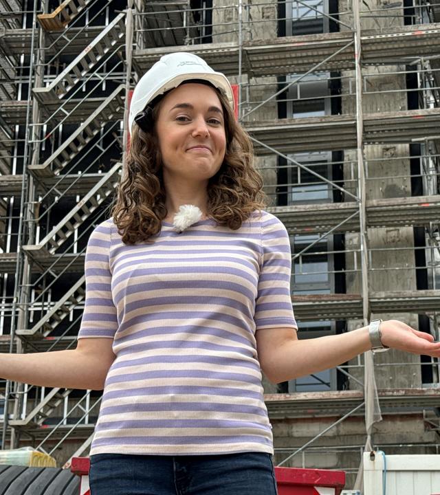 Reporterin Lotte steht vor einem Gerüst