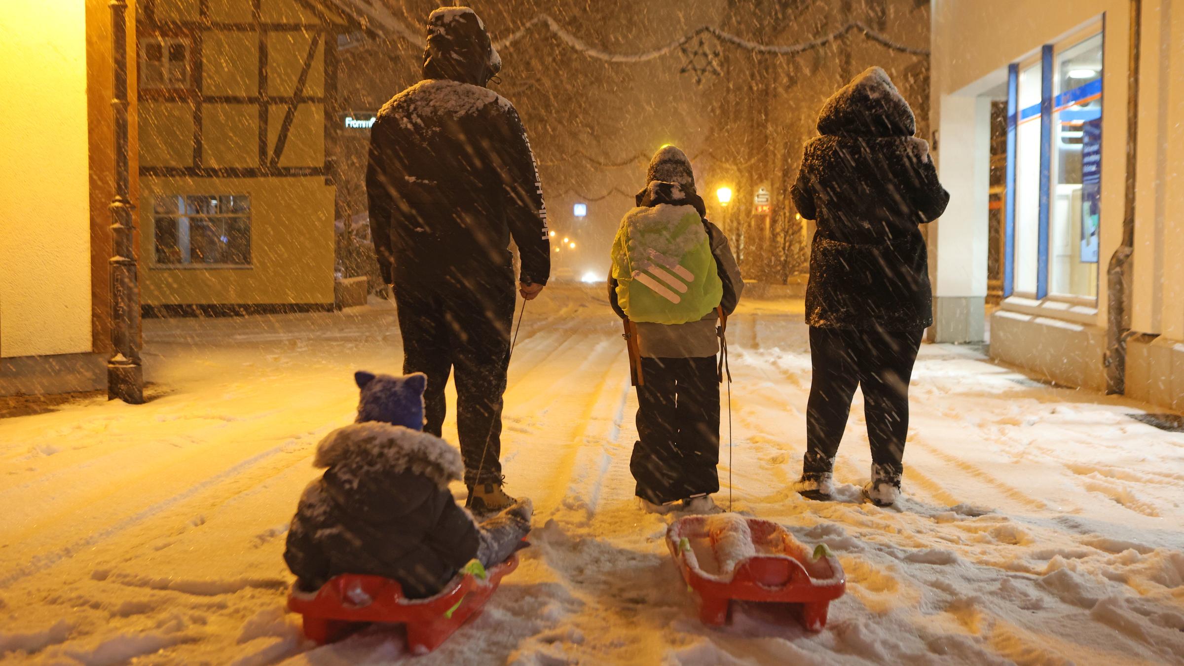 Schnee liegt auf einem Verkehrsschild und Hinweisschild mit der Aufschrift Schule vor einer Schule.