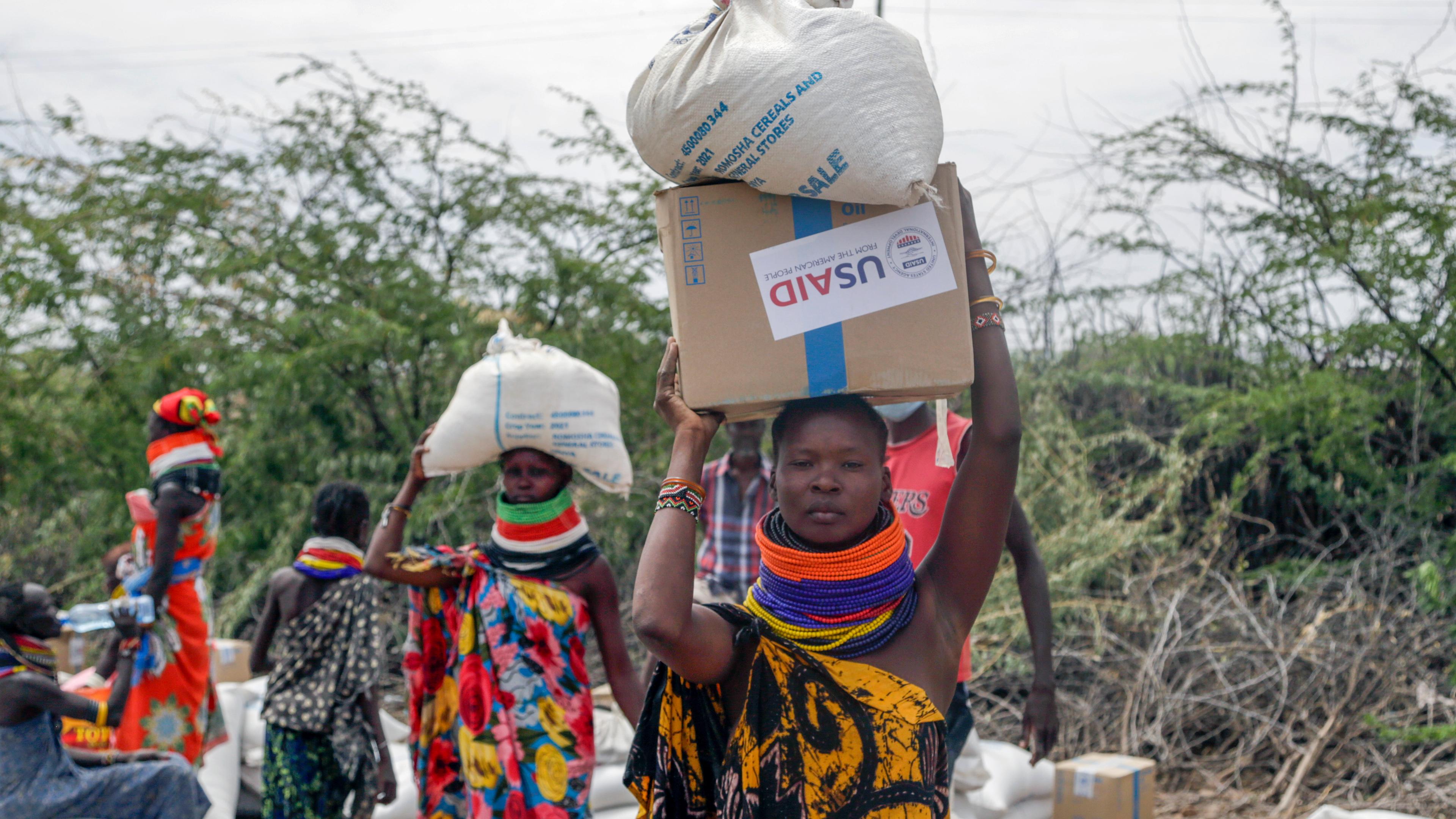 Frauen tragen Säcke mit Essen von USAID in Kenia.