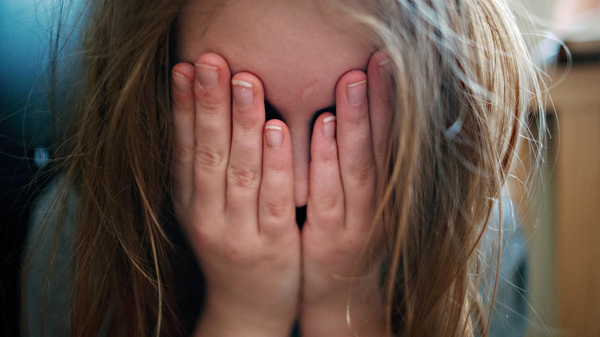 Ein Mädchen hält sich die Hände vor die Augen, weil es vor etwas Angst hat