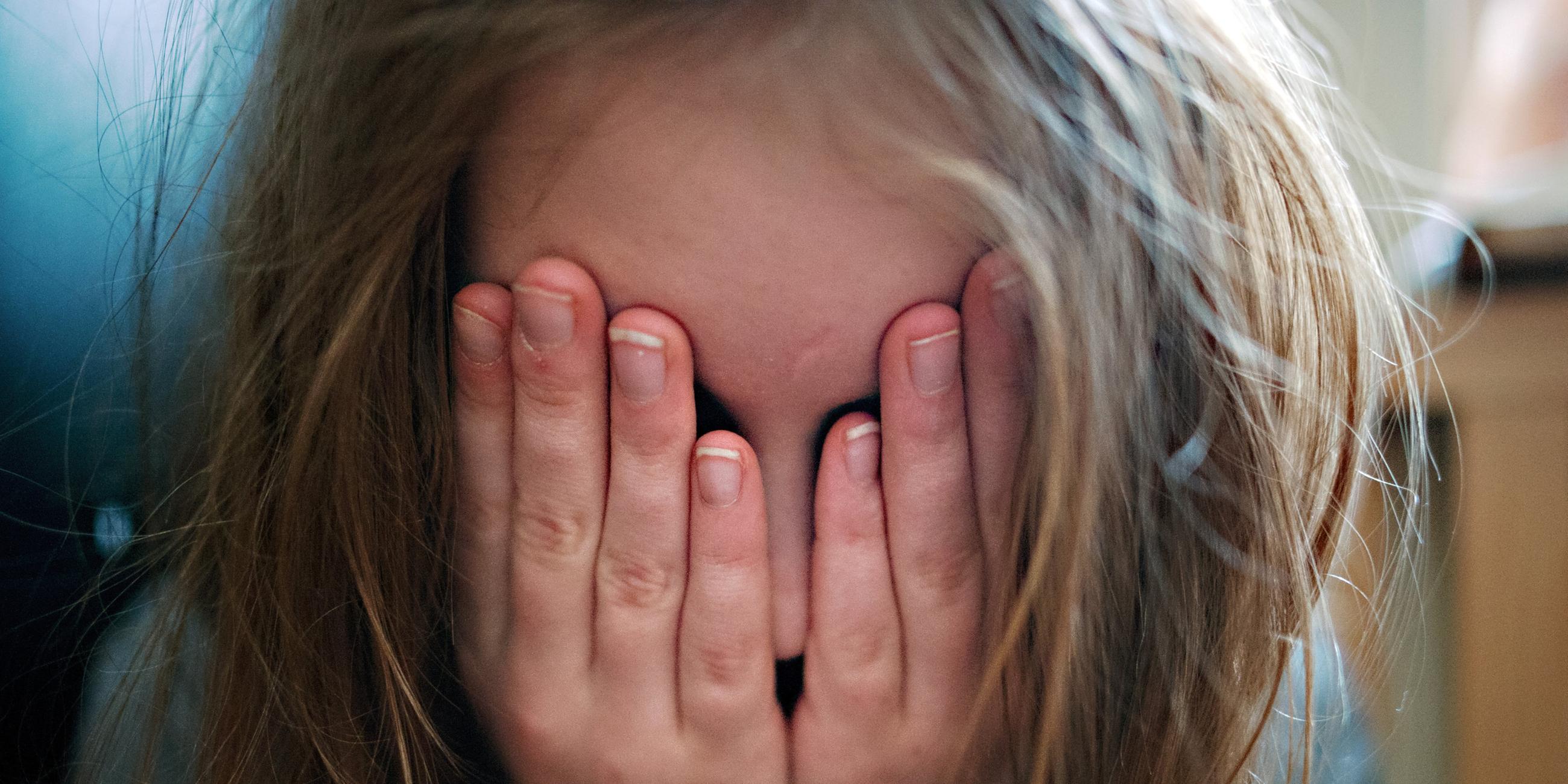 Ein Mädchen hält sich die Hände vor die Augen, weil es vor etwas Angst hat