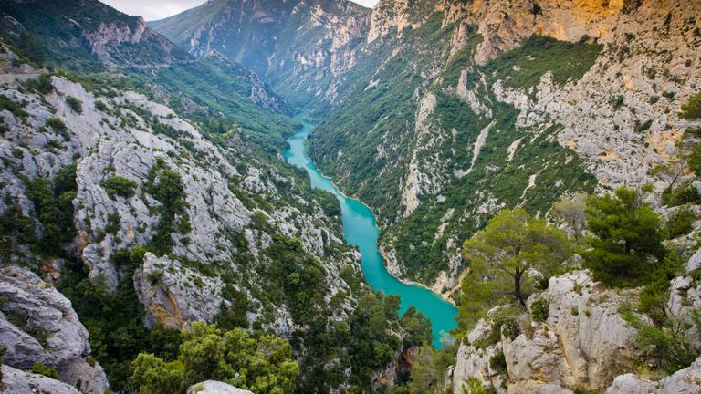 Man sieht Berge und einen türkisblauen Fluss im Tal