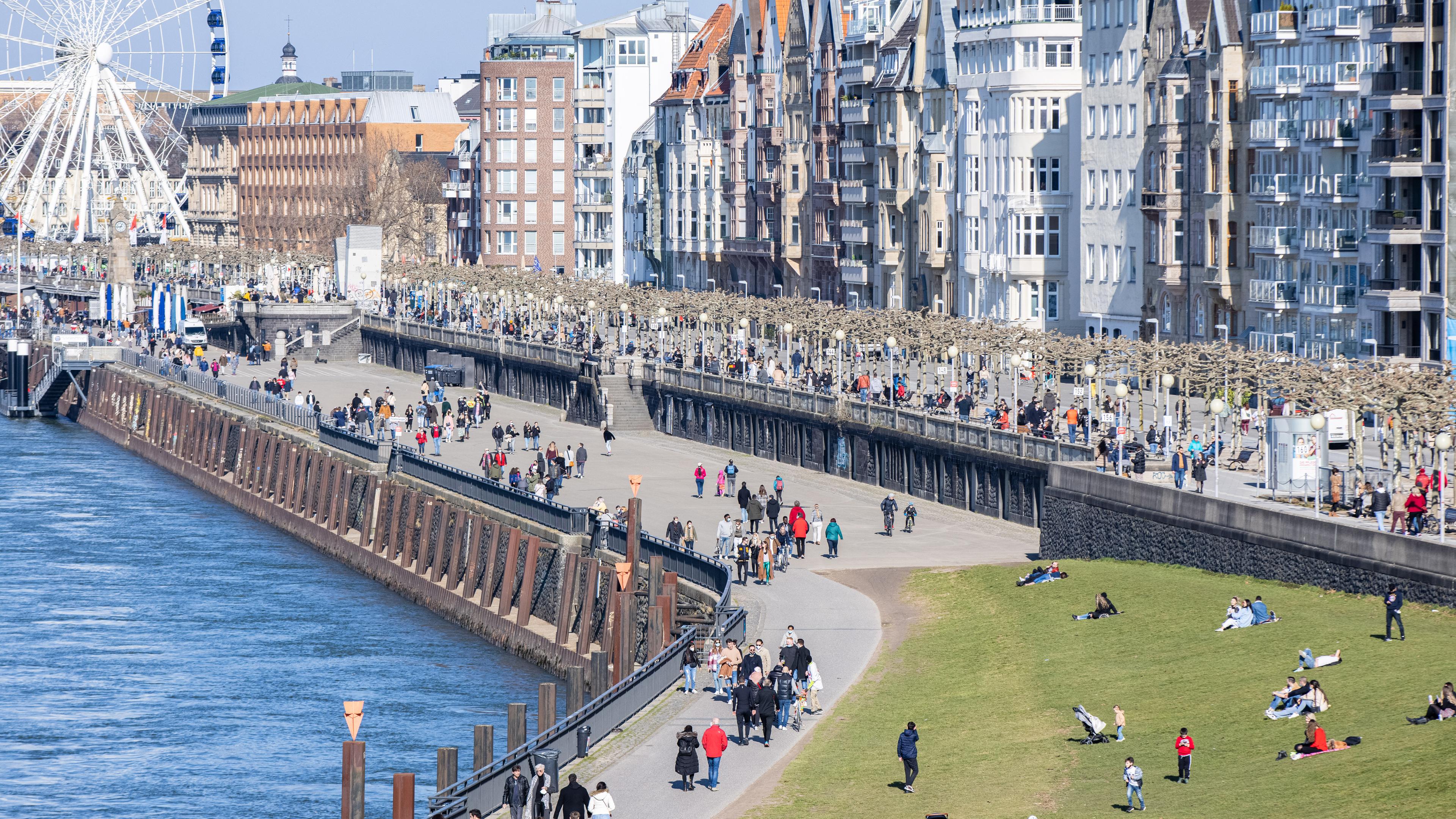 Düsseldorf: Menschen gehen am Sonntag bei Sonnenschein am Rheinufer spazieren. Seit Freitag hängen am Rheinufer Hinweisschilder mit der Aufschrift "Verweilverbotszone - Bitte gehen sie weiter!". 