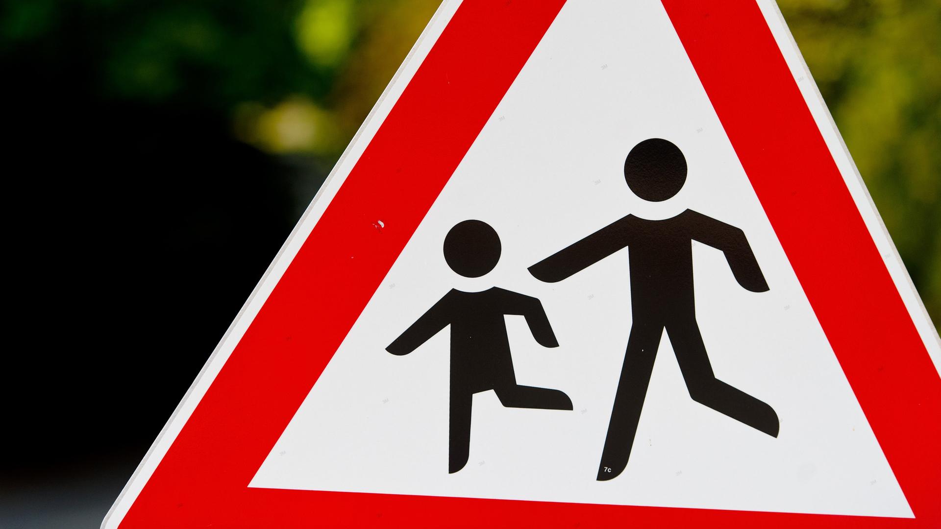 Zwei spielende Kinder als Figuren auf einem dreieckigen Warnschild