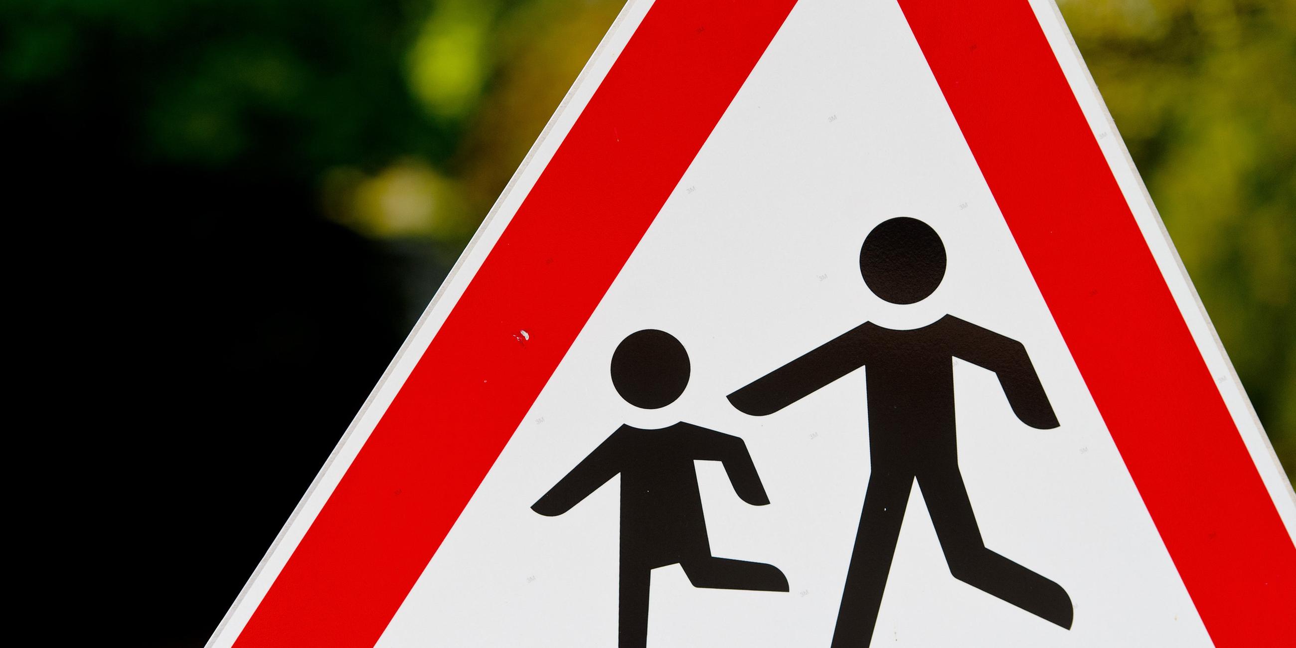 Zwei spielende Kinder als Figuren auf einem dreieckigen Warnschild