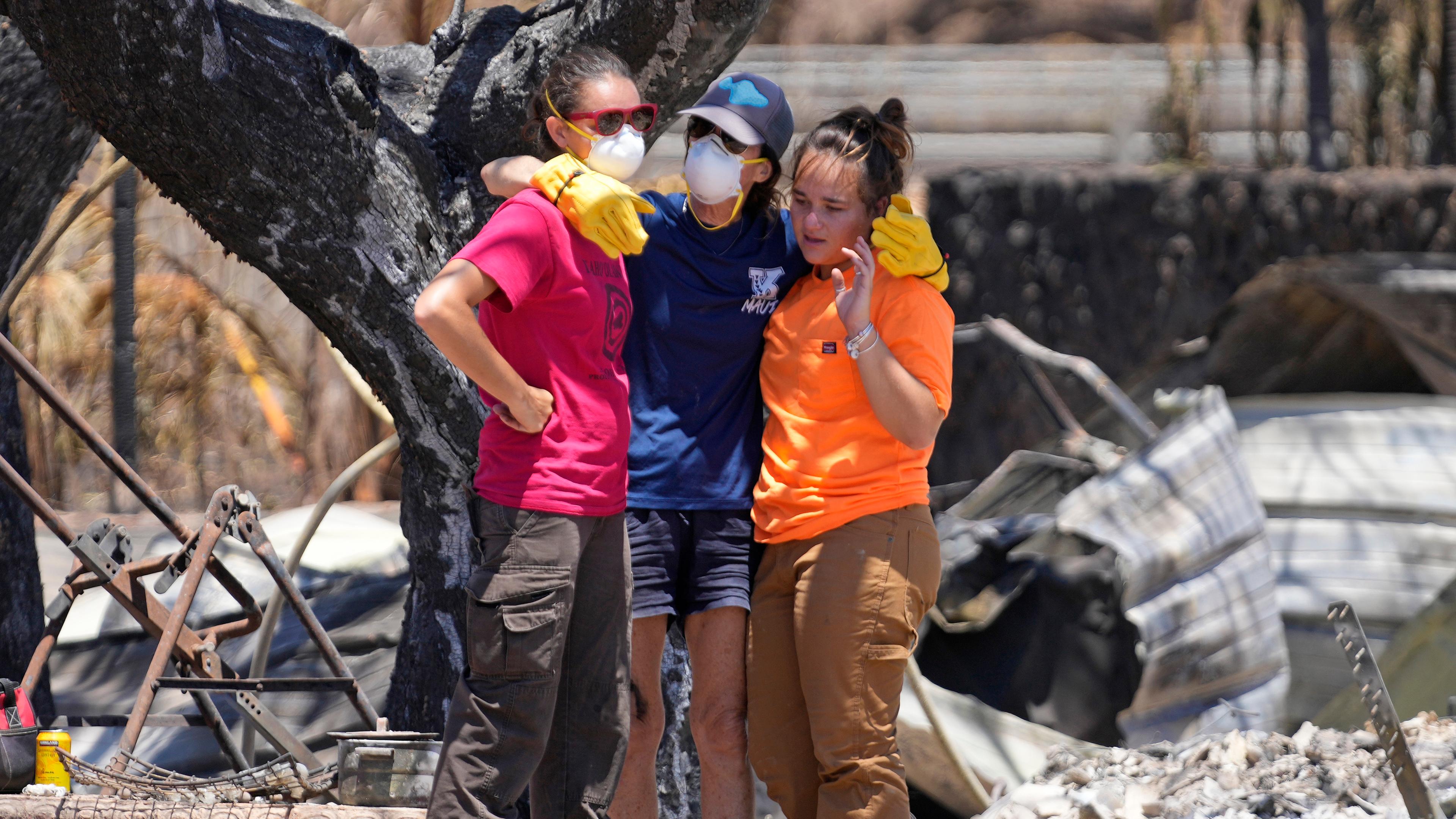 Frauen umarmen sich, nachdem sie sich durch die Trümmer eines von einem Waldbrand zerstörten Hauses gegraben haben,