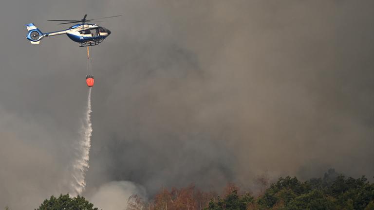Löschhubschrauber wirft Wasser über Baumkronen ab
