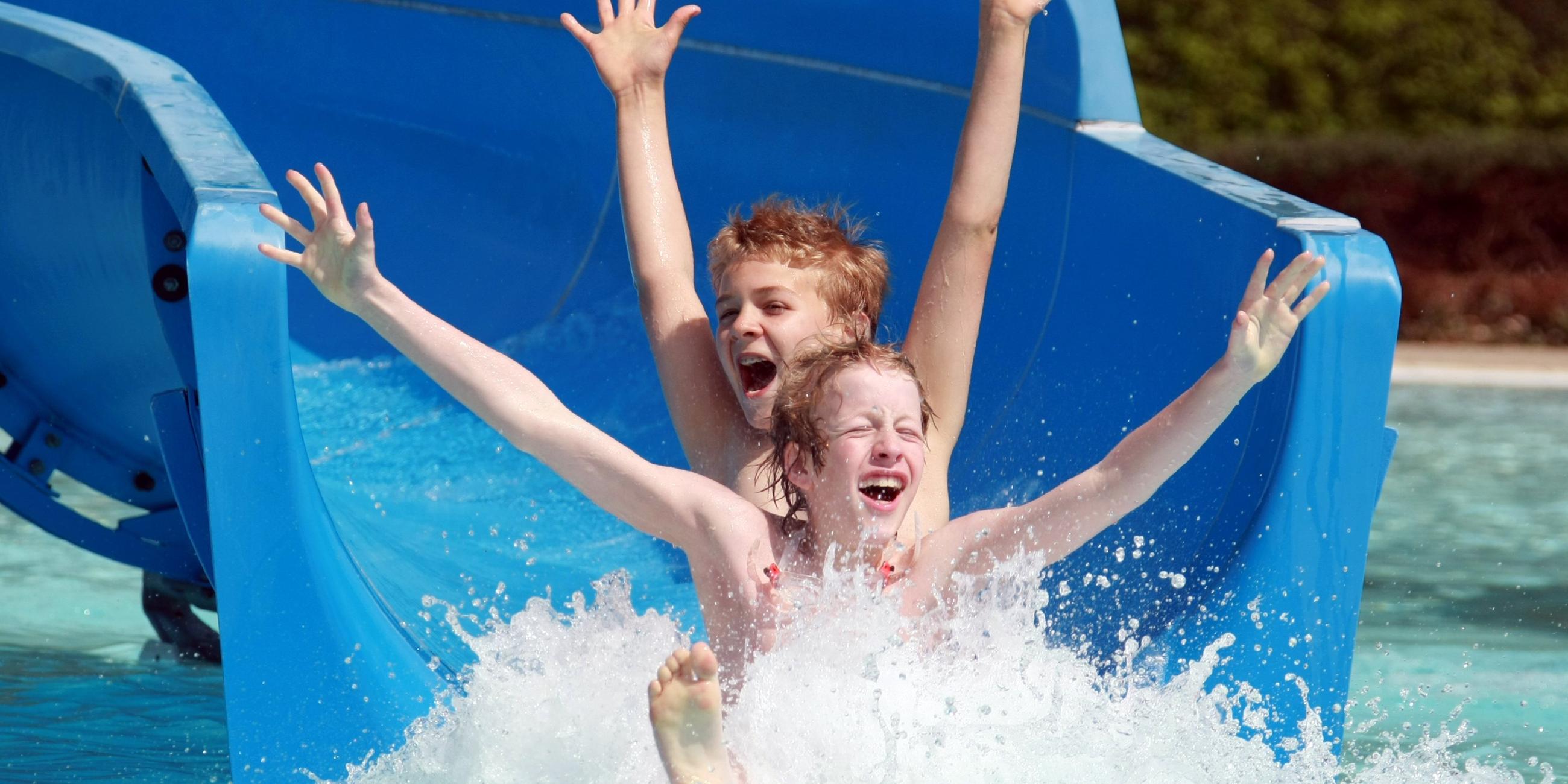 Kinder rutschen Wasserrutsche hinunter 