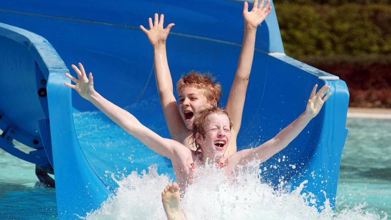 Kinder rutschen Wasserrutsche hinunter 