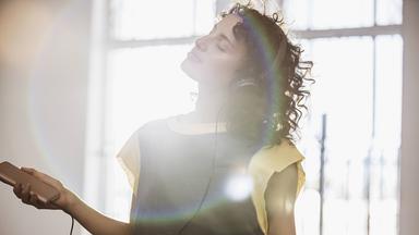 Eine junge Frau hört Musik und tanzt 