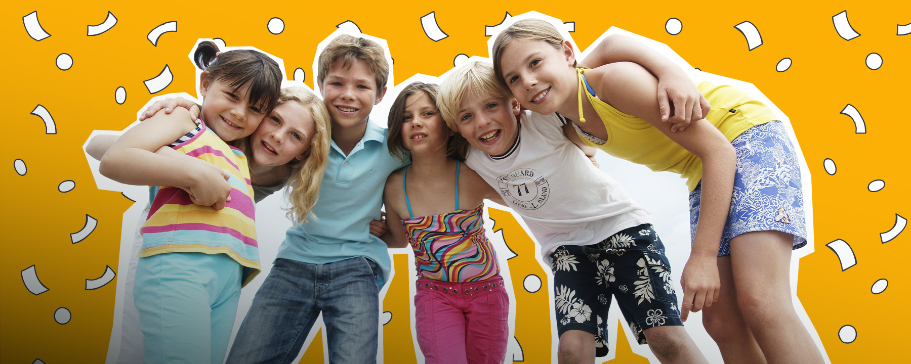 Sechs Kinder liegen sich lachend in den Armen.