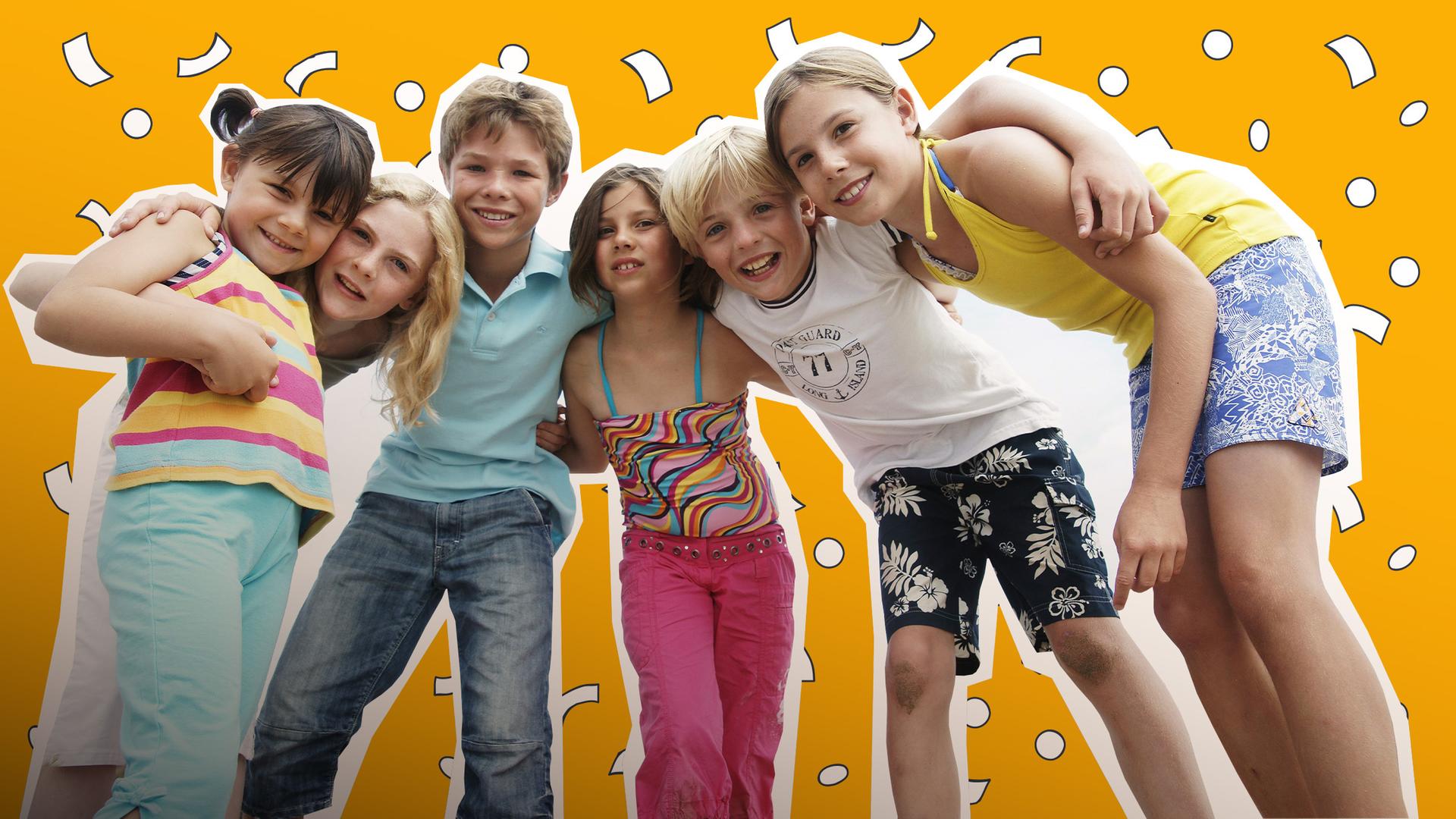 Sechs Kinder liegen sich lachend in den Armen.