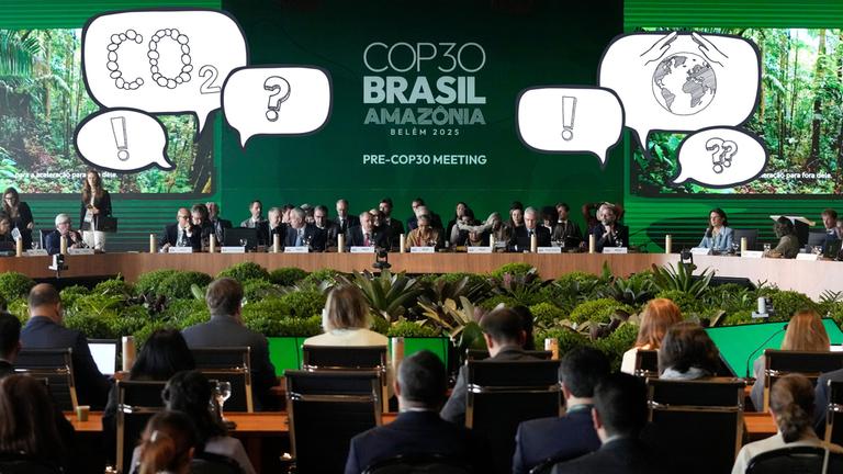 Menschen sitzen in einem grün dekorierten Konferenzsaal, darüber Comic-Sprechblasen mit Ausrufezeichen ,CO2, eine Weltkugel mit schützenden Händen darüber und Fragezeichen