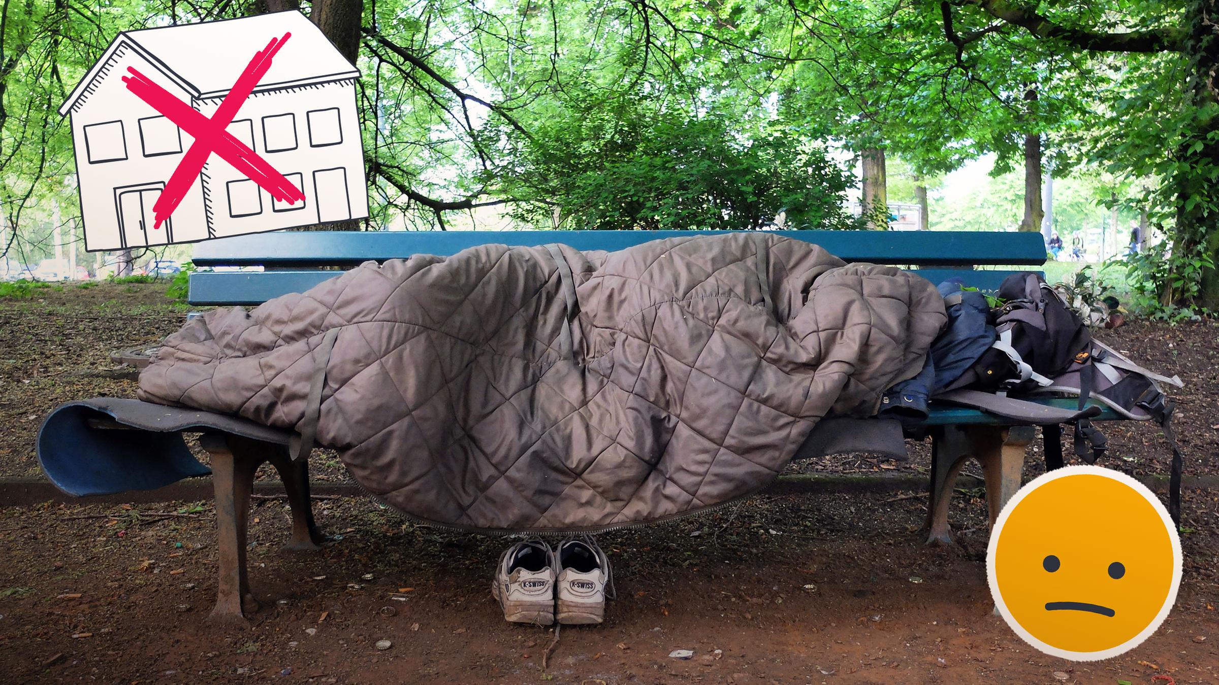 Ein obdachloser Mensch, zugedeckt mit einer Decke, auf einer blauen Parkbank im Wald