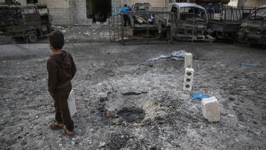 Archiv: Ein syrisches Kind geht an einem Loch im Boden vorbei, das sich nach einem Raketenbeschuss gebildet hat, aufgenommen am 03.03.2020 in Idlib, Syrien